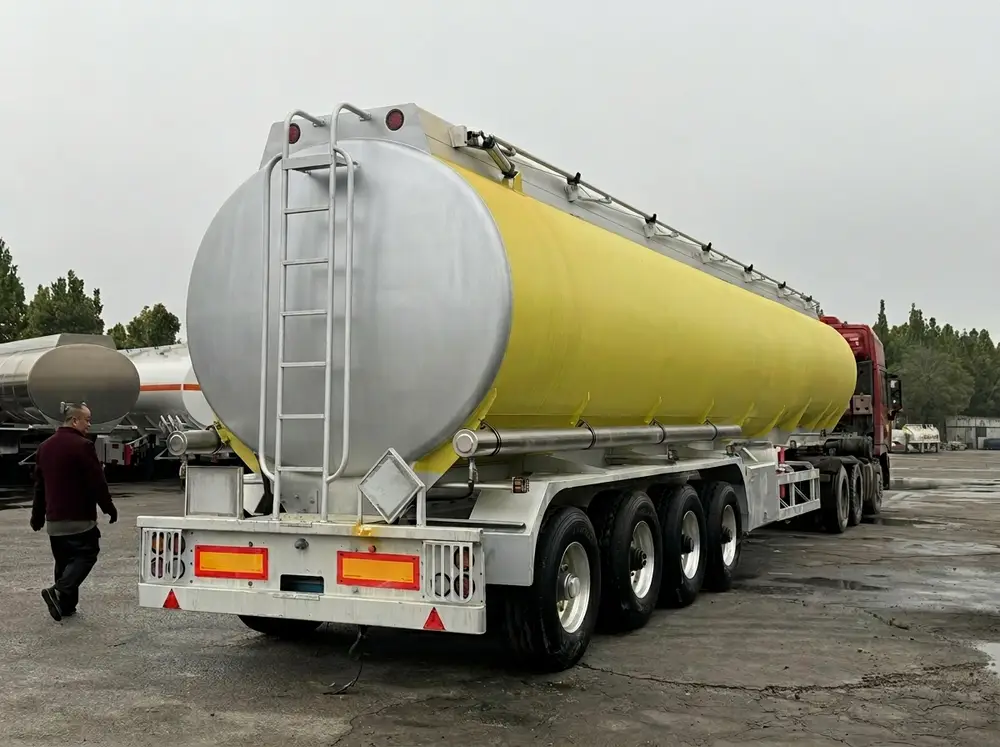 Rear view of 55 CBM fuel tanker showing 4-axle chassis, rear lights, ladder access, and reflective safety markers
