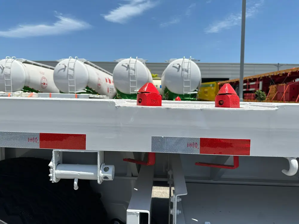 Two twist locks, a lashing winch, and red-white reflective tape along the edge of the checkered deck.