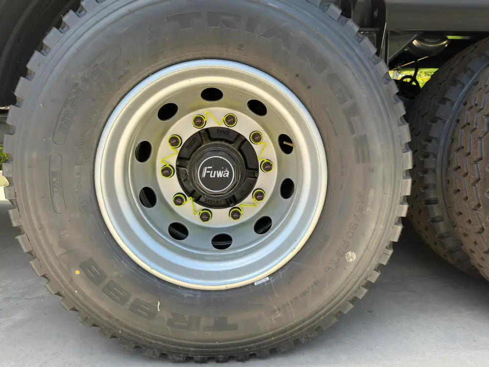 Triangle 12R22.5 tire on a FUWA hub with yellow loose wheel-nut indicators fitted across the studs.