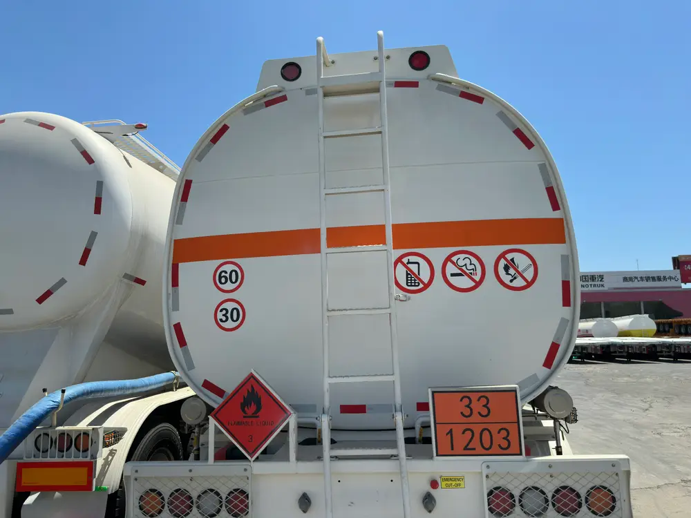 The rear head carries the UN 1203 orange plate, Class 3 flammable liquid diamond, speed roundels, and the access ladder.
