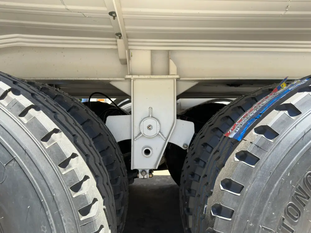 The mechanical leaf-spring equalizer hanger sits between axle pairs under the 54,000 liter tank.