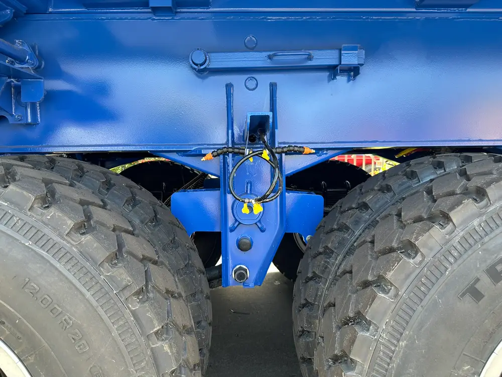 Deep-block 12.00R20 mining tire, heavy hub, and brake air lines on the heavy duty rear dump trailer running gear.