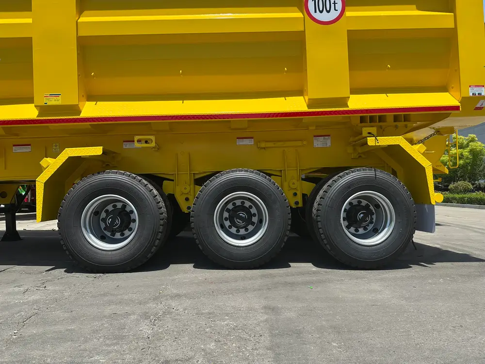Three 12.00R20 deep-block mining tires on 10-stud steel rims under the 100 t badge of the tipper body.
