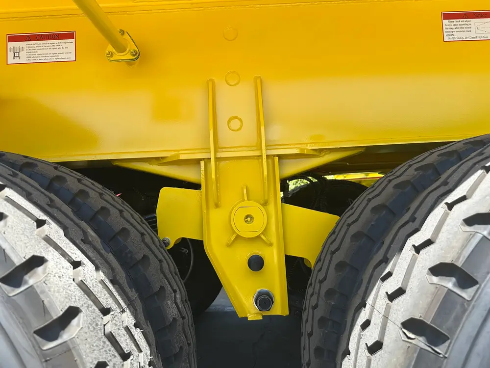 Heavy mechanical suspension equalizer and hanger bracket between two mining-tread tires on the tipper trailer.