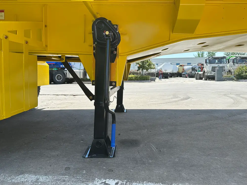The two-speed landing gear leg with wide sand shoe deployed under the front of the yellow tipper body.